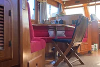 Interior of 1991 Trader 47 yacht with wooden furnishings and red seating.