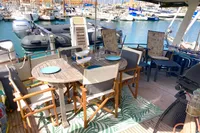 Outdoor dining area on 1991 Trader 47 yacht, featuring wooden furniture and marina view.