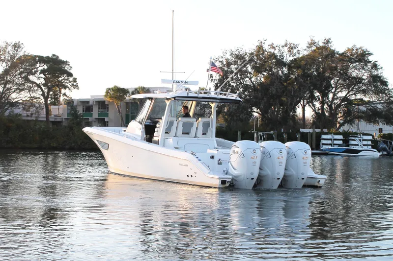  Yacht Photos Pics 2023 Pursuit S 378 Sport boat on calm water with trees in the background.