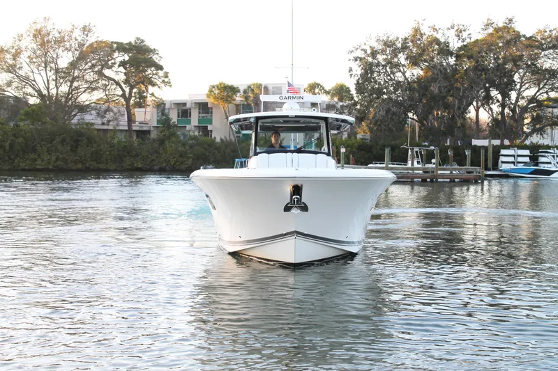  Yacht Photos Pics 2023 Pursuit S 378 Sport boat cruising on a calm river with trees in the background.