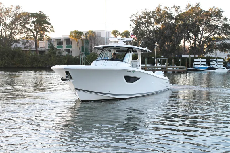  Yacht Photos Pics 2023 Pursuit S 378 Sport boat cruising on a calm waterway near a marina.