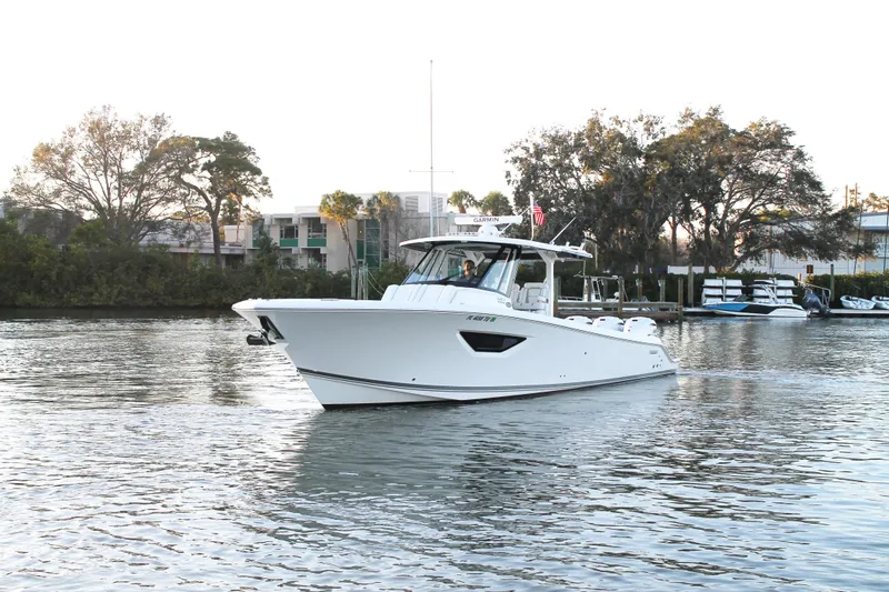  Yacht Photos Pics 2023 Pursuit S 378 Sport boat cruising on a calm waterway, surrounded by trees.
