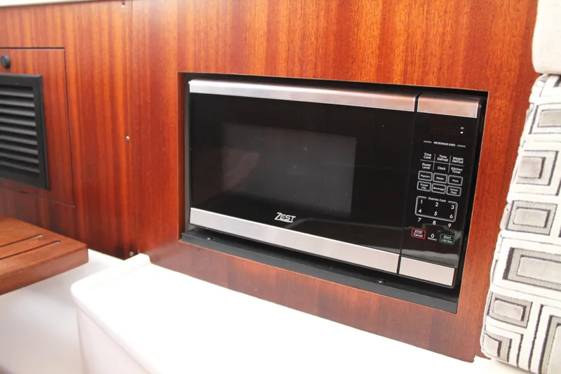  Yacht Photos Pics Built-in microwave in 2023 Pursuit S 378 Sport boat interior, featuring wood paneling.