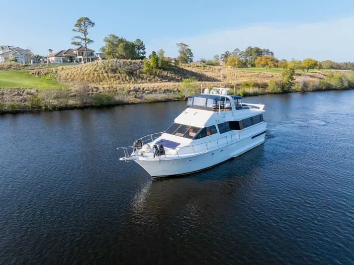  Yacht Photos Pics 1989 Viking 63 Motor Yacht cruising on a serene river with scenic landscape.