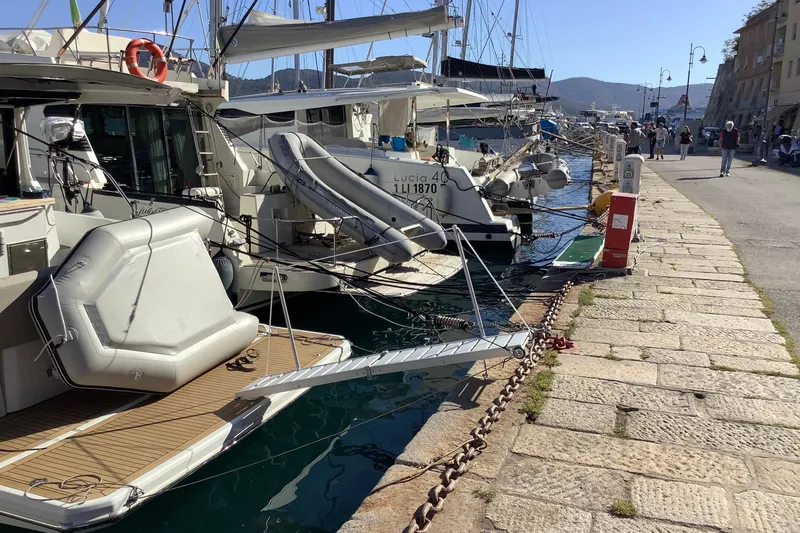  Yacht Photos Pics Docked boats including a 2016 Sealine C330 at a sunny marina with people walking nearby.