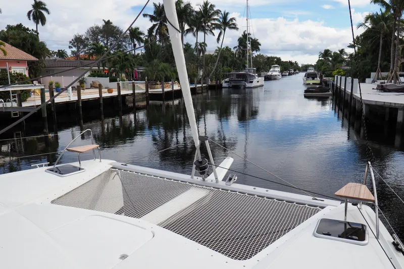Khonsu Yacht Photos Pics 2023 Fountaine Pajot Isla catamaran docked in a scenic canal with palm trees.