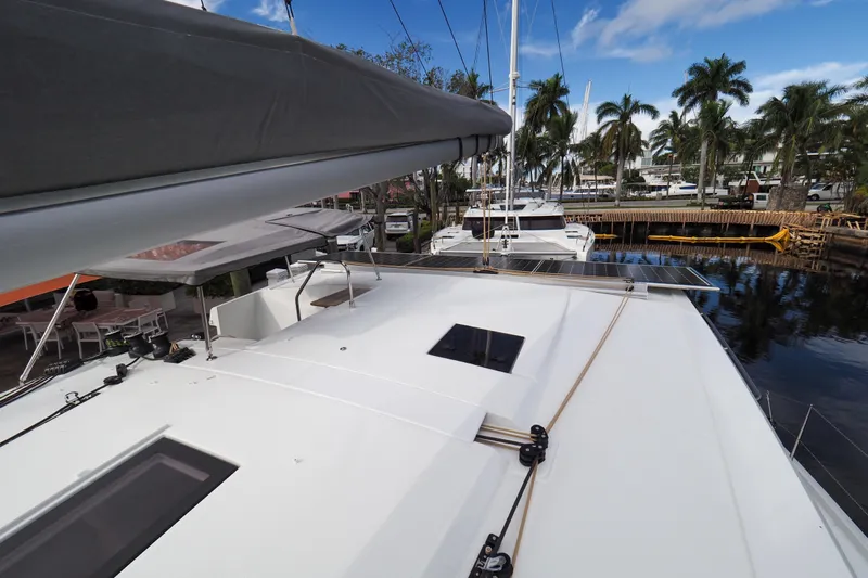 Khonsu Yacht Photos Pics 2023 Fountaine Pajot Isla catamaran docked, showcasing sleek deck design and tropical surroundings.