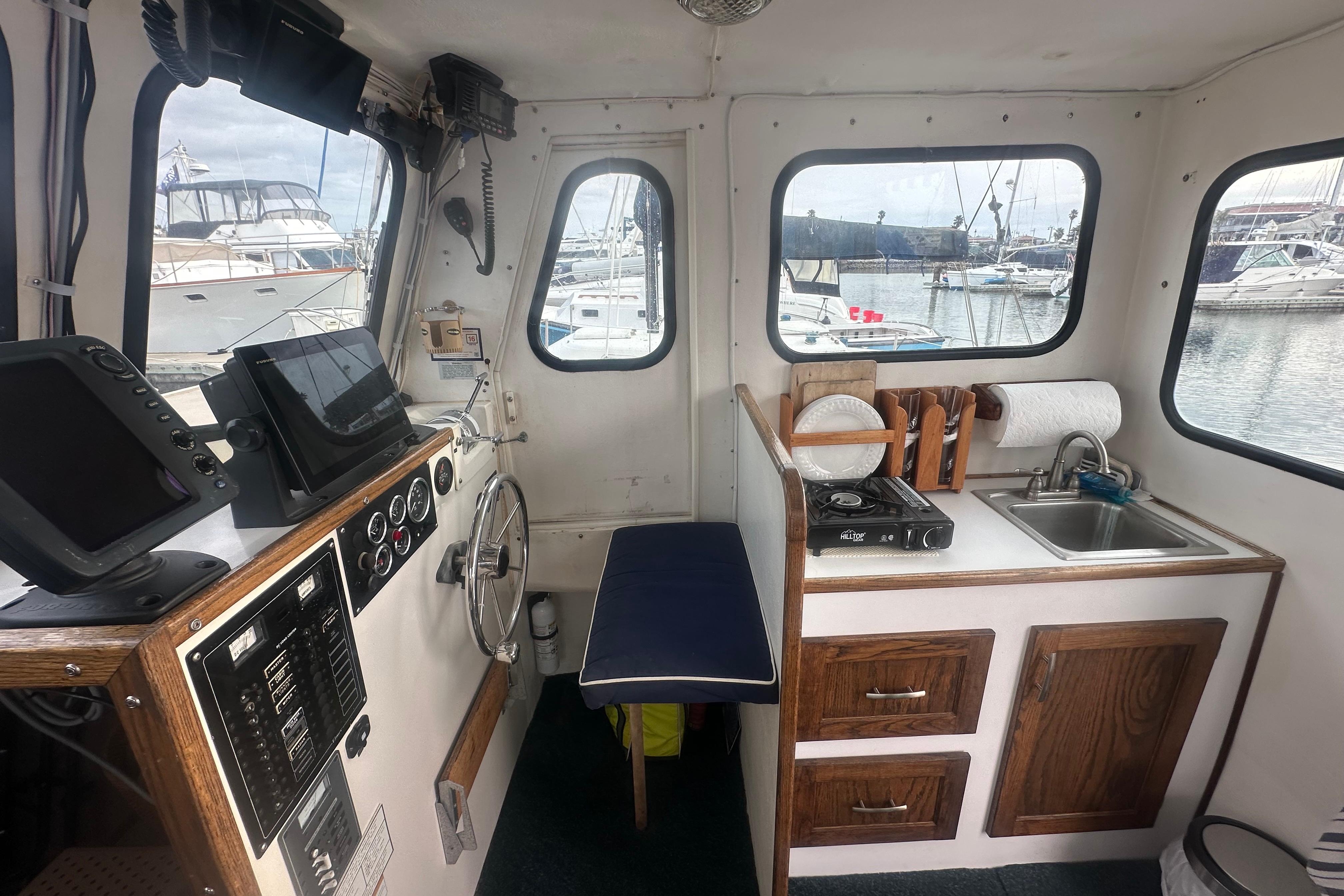 Interior of a 1999 Samson East Coast Lobster boat with helm, kitchen, and marina view.