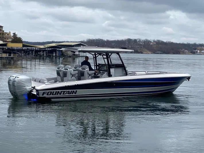 Yacht Photos Pics 2023 Fountain 34 SC boat on a calm lake under cloudy skies.