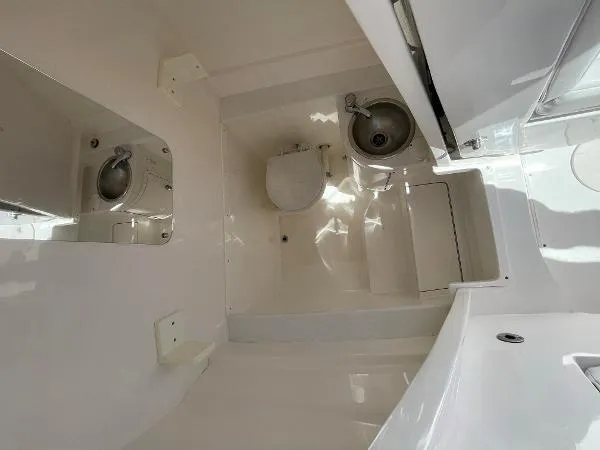  Yacht Photos Pics 2013 Intrepid 327 OPEN boat bathroom with toilet and sink, featuring a sleek white interior.