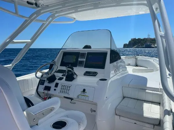  Yacht Photos Pics Intrepid 327 OPEN 2013 boat cockpit with steering wheel and navigation screens, on open sea.
