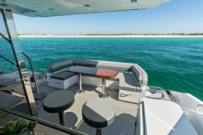  Yacht Photos Pics 2018 Cruisers Yachts 60 Fly deck with seating, overlooking turquoise ocean and sandy shore.