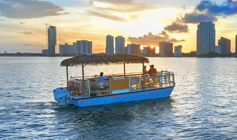 Tiki International Yacht Photos Pics Tiki-themed Beachcat 26 boat cruising at sunset near city skyline, 2023 model.