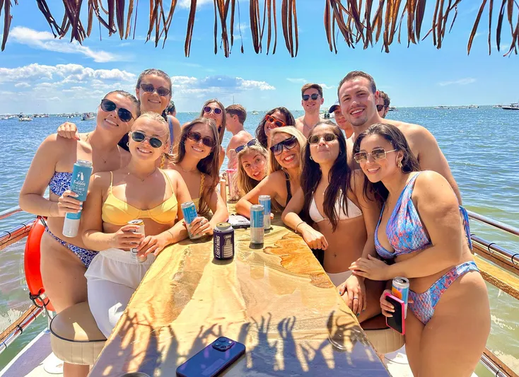 Tiki International Yacht Photos Pics Group enjoying sunny day on 2023 Beachcat 26 Tiki COI boat, holding drinks.