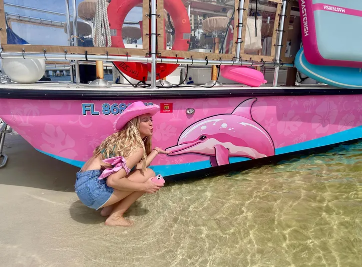 Tiki International Yacht Photos Pics Woman in pink hat beside 2023 Beachcat 26 Tiki COI boat with dolphin design.