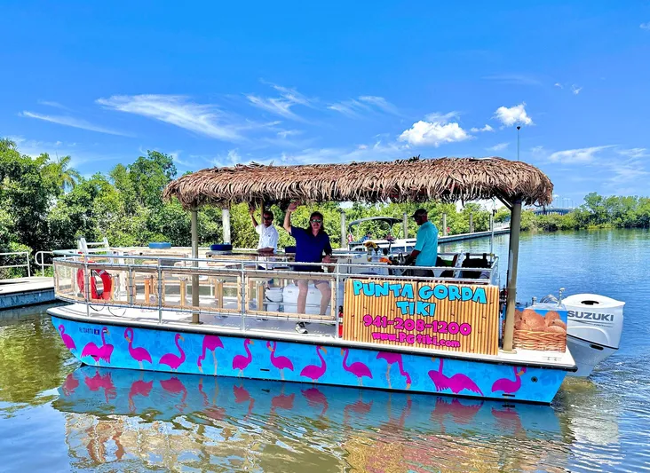 Tiki International Yacht Photos Pics 2023 Beachcat 26 Tiki COI boat with tiki roof and flamingo design on a sunny day.