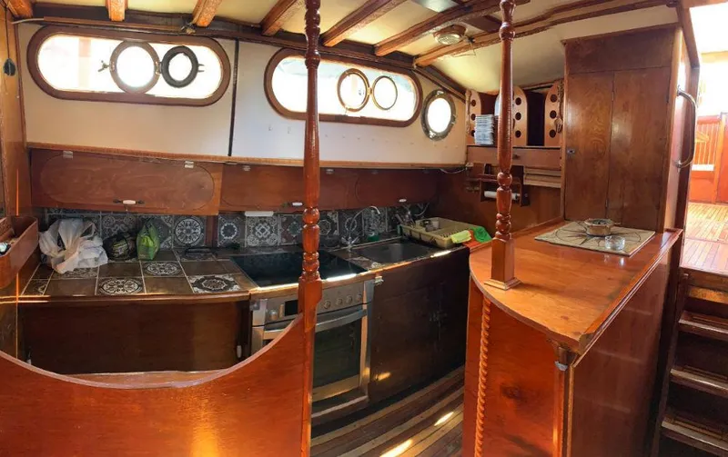  Yacht Photos Pics Interior of a 1981 traditional motor sailer, featuring a wooden kitchen with porthole windows.