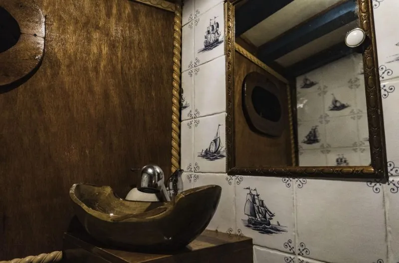  Yacht Photos Pics Vintage sailboat bathroom with nautical-themed tiles, wooden sink, and mirror.