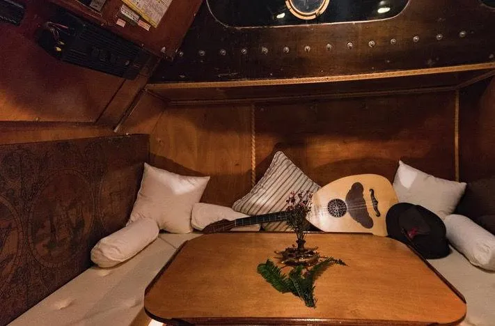  Yacht Photos Pics Cozy cabin interior of 1981 Traditional Motor Sailer with pillows, guitar, and wooden table.