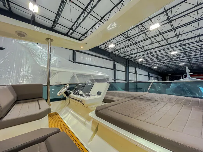 Total Package Yacht Photos Pics 2016 Prestige 680 Flybridge yacht interior with seating and control panel in a spacious warehouse.