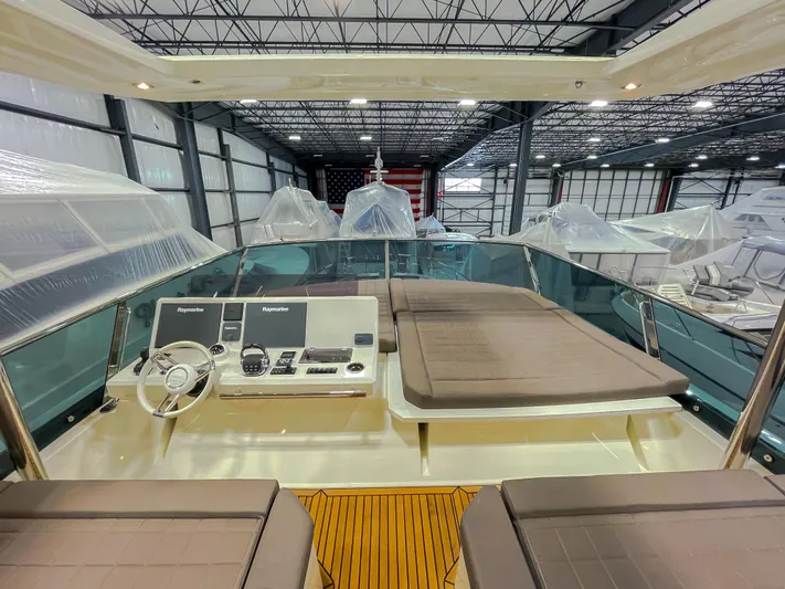 Total Package Yacht Photos Pics 2016 Prestige 680 Flybridge yacht interior with helm and seating in a spacious warehouse.