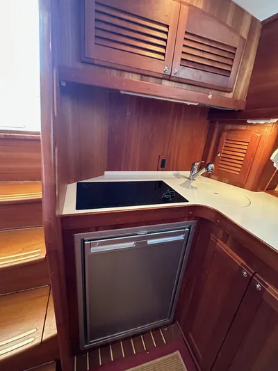 Bay Saddle Yacht Photos Pics 2005 Sabre 38 Hardtop Express galley with wood cabinetry, stovetop, and compact refrigerator.