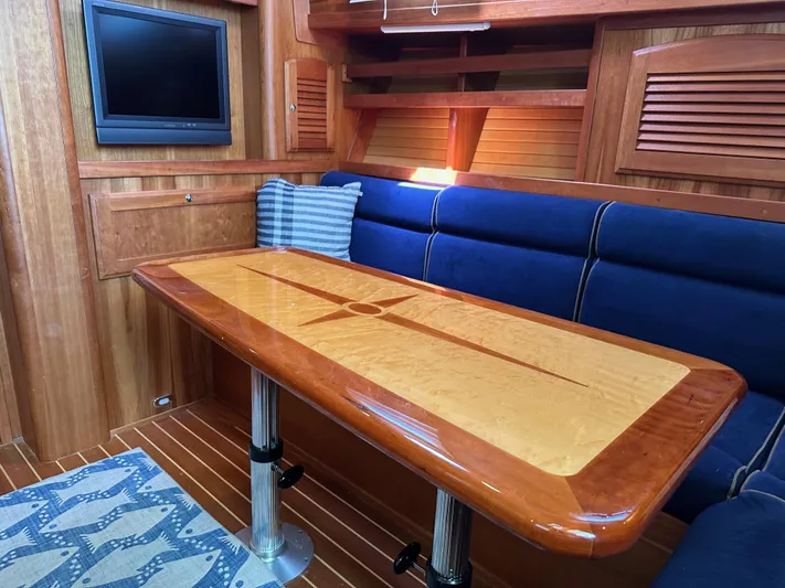 Bay Saddle Yacht Photos Pics 2005 Sabre 38 Hardtop Express interior with wooden table, blue seating, and wall-mounted TV.