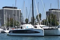 2018 Outremer 4X catamaran docked in marina with modern buildings in background.