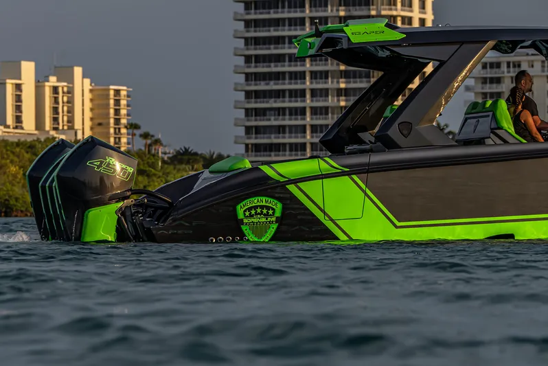  Yacht Photos Pics 2024 Adrenaline Reaper boat with vibrant green accents on water, cityscape background.