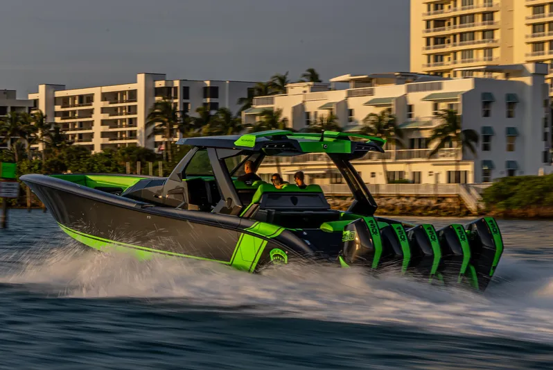  Yacht Photos Pics 2024 Adrenaline Reaper speedboat cruising on water near modern buildings.