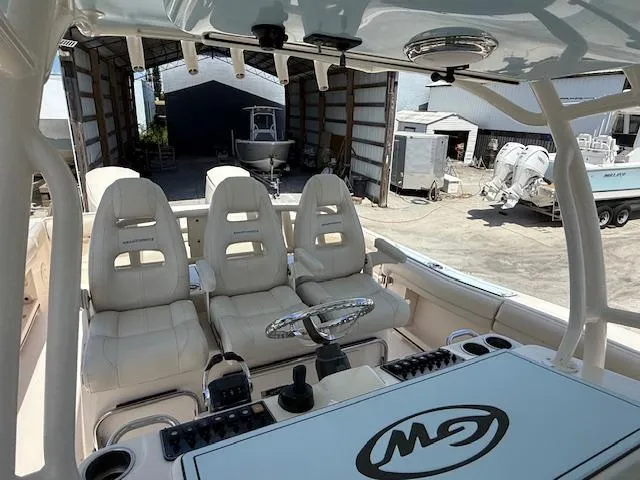 336-311 Brokerage Ron Yacht Photos Pics 2018 Grady-White Canyon 336 boat interior with three seats and steering wheel in a boatyard.