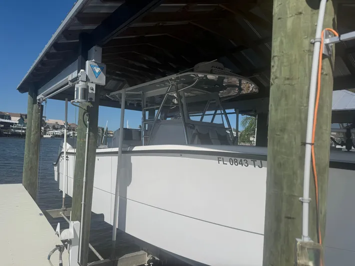  Yacht Photos Pics 2023 Invincible 33 Catamaran docked under a wooden shelter by the water.