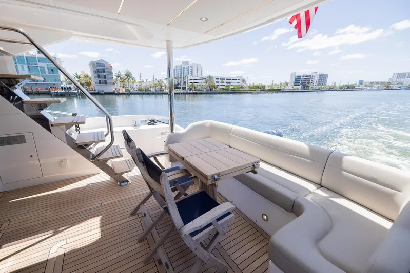 Sea Zar Yacht Photos Pics 2019 Sunseeker Manhattan 66 yacht deck with seating and table, overlooking waterfront buildings.