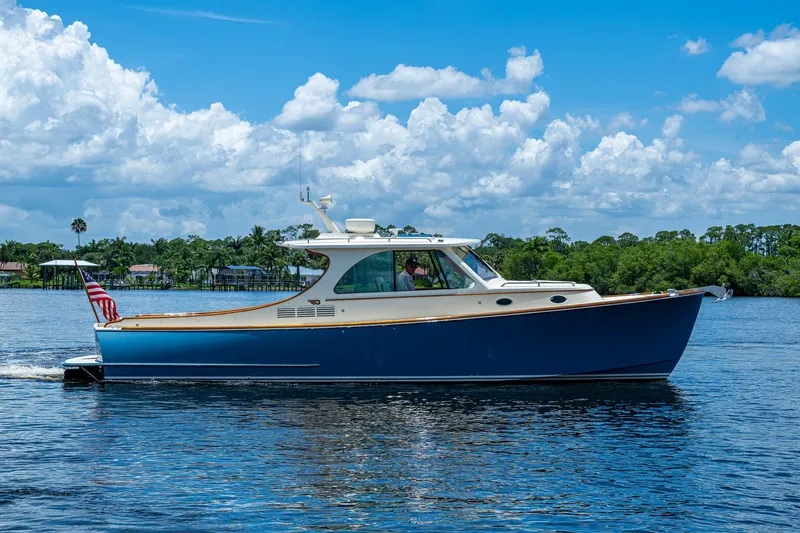 San Marco Yacht Photos Pics 2016 Hinckley Talaria 34 cruising on a sunny day with lush greenery in the background.