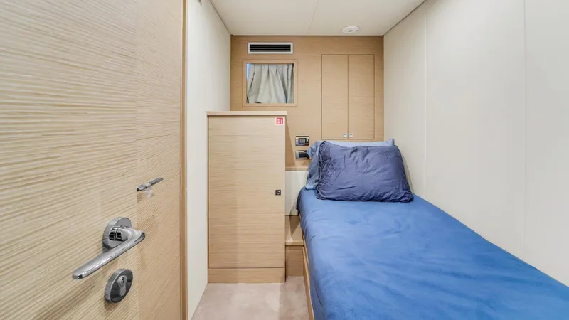 Aurora Yacht Photos Pics 2022 Ferretti Yachts 1000 cabin with single bed, blue bedding, and modern wood paneling.