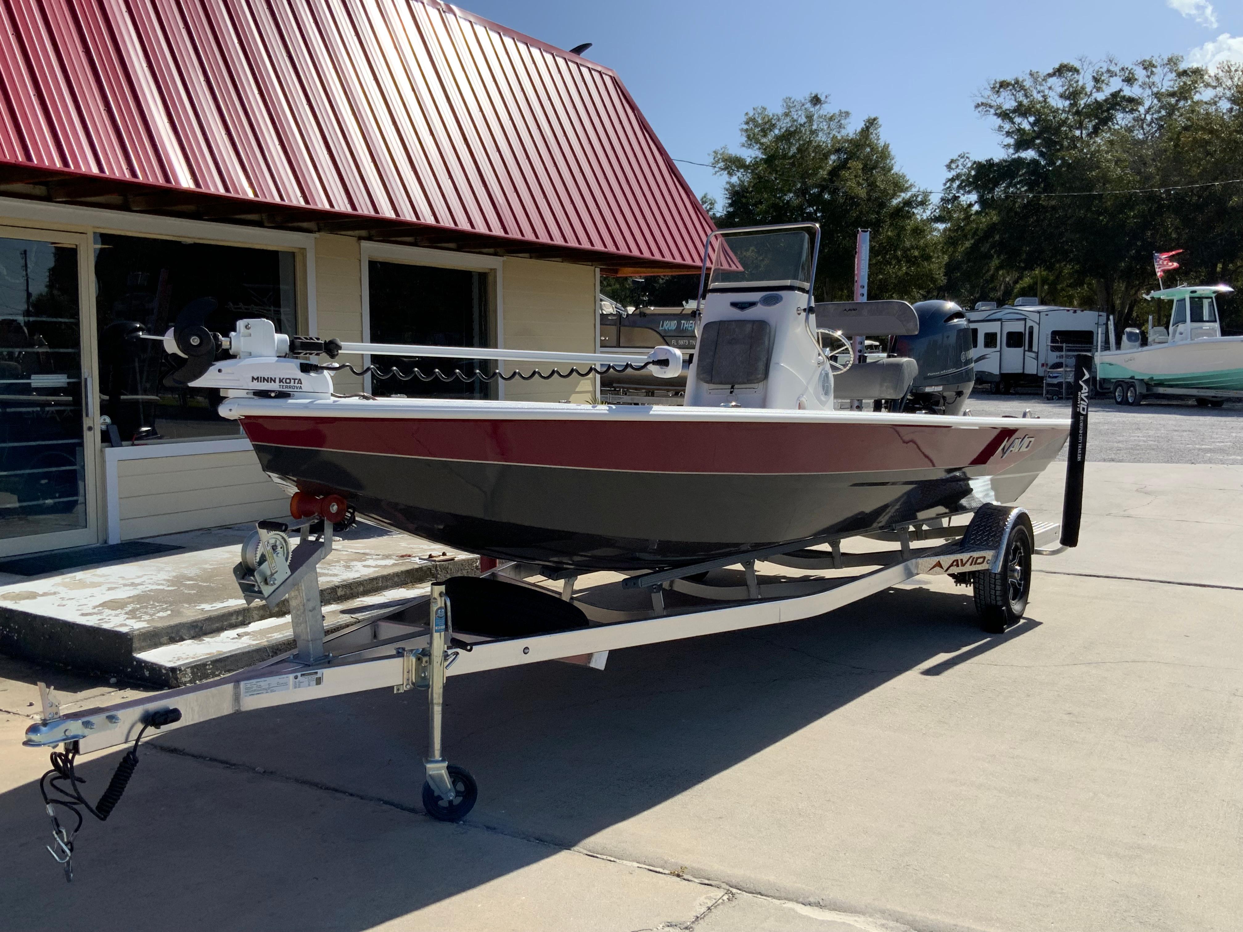 2023 Avid 21 Mag boat on trailer outside dealership with red roof.