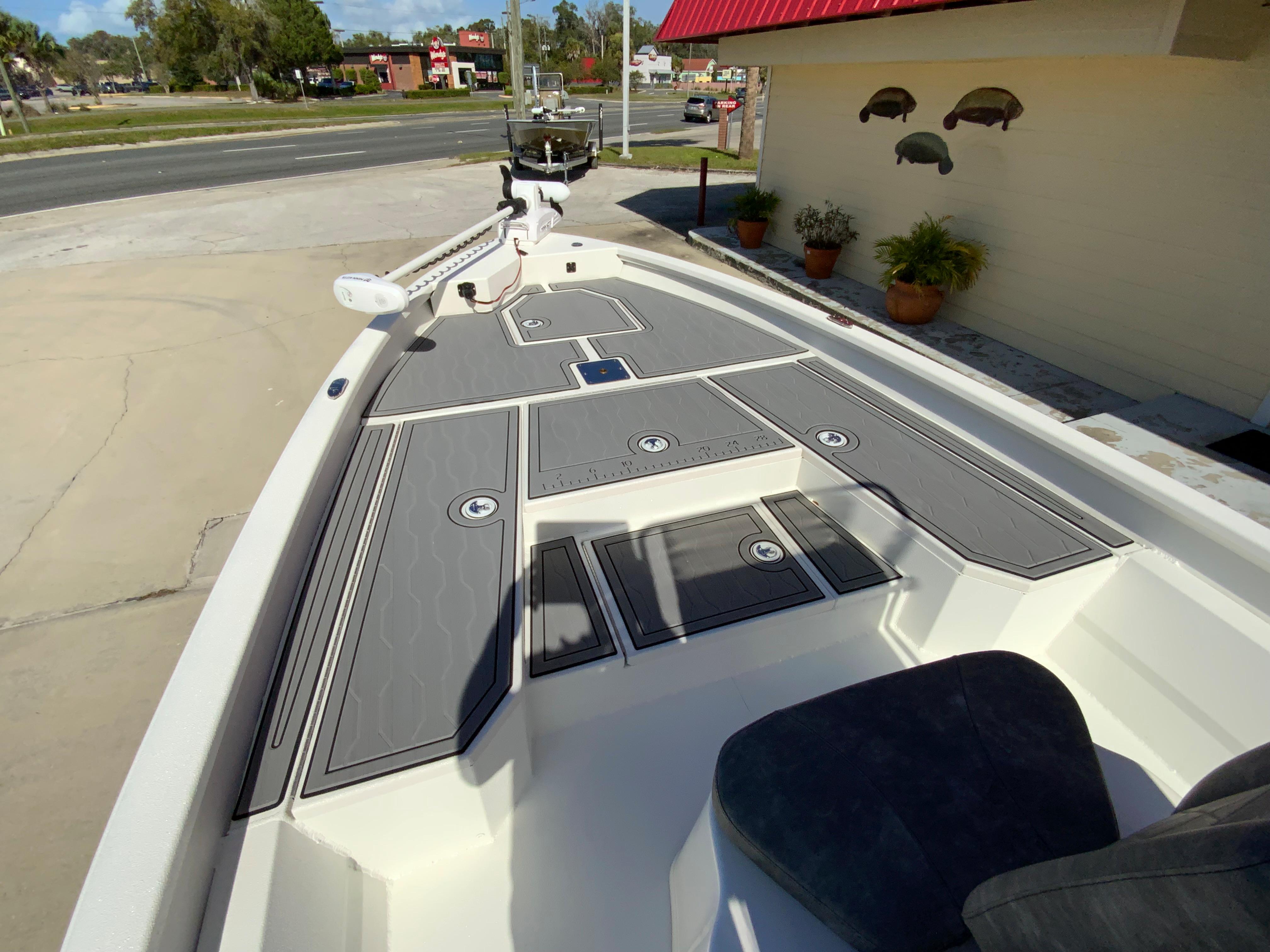 2023 Avid 21 Mag boat with gray deck, docked near a building.