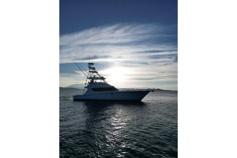 Yacht Photos Pics 2009 Hatteras 60 Convertible yacht silhouetted against a sunset on the open sea.
