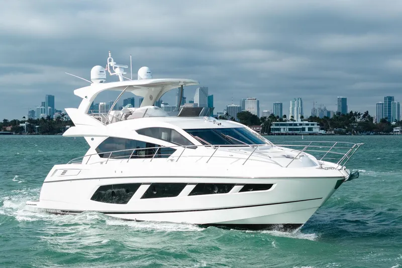  Yacht Photos Pics 2016 Sunseeker Manhattan 65 yacht cruising on open water with city skyline backdrop.