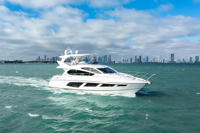  Yacht Photos Pics 2016 Sunseeker Manhattan 65 yacht cruising on open water with city skyline backdrop.
