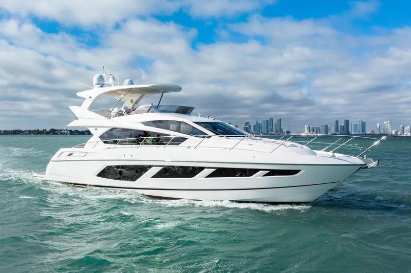  Yacht Photos Pics 2016 Sunseeker Manhattan 65 yacht cruising on open water with city skyline backdrop.