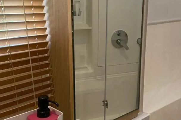  Yacht Photos Pics Modern bathroom with glass shower door, wooden blinds, and pink soap dispenser. Aquila 42, 2023 model.