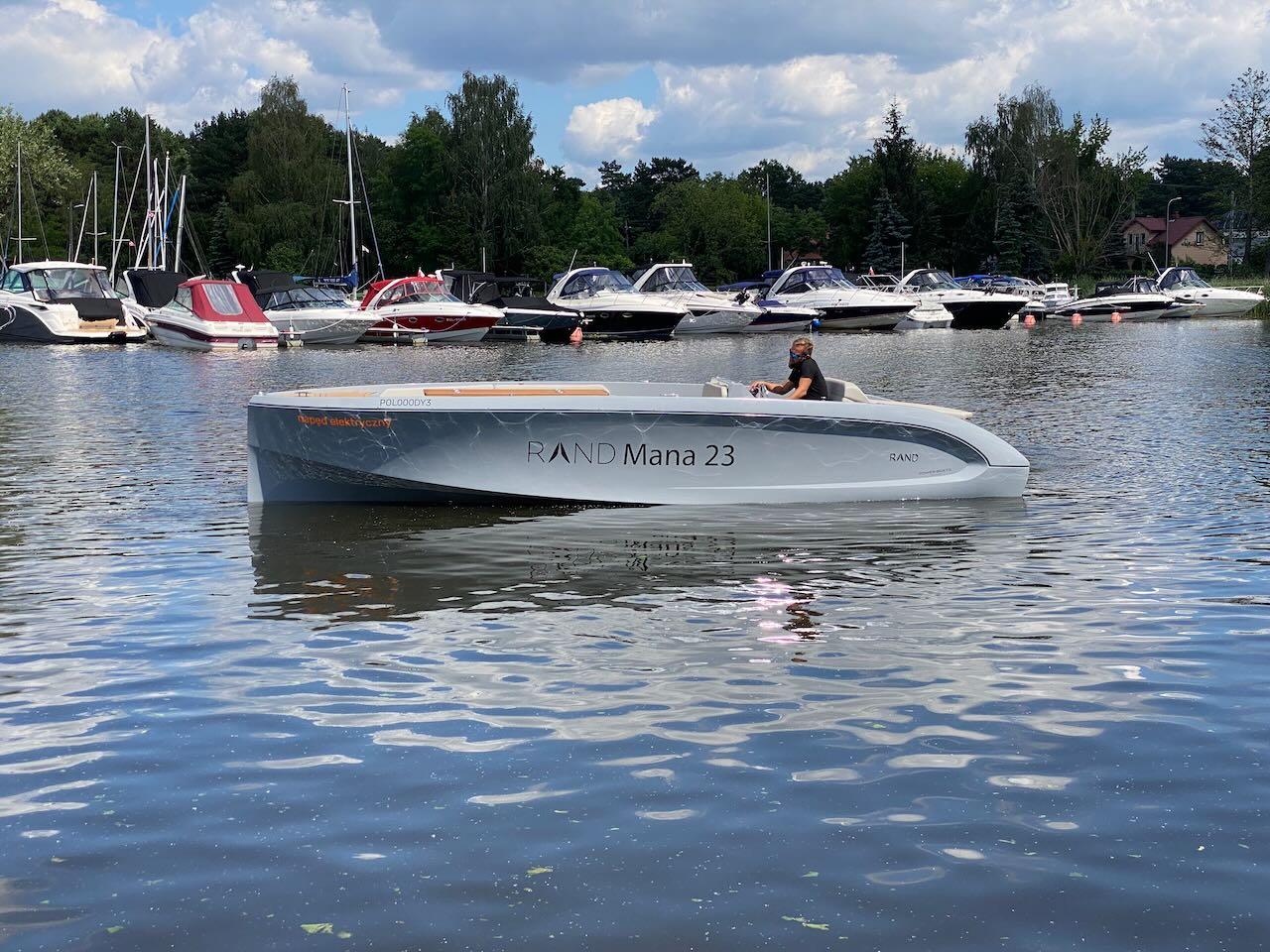 2021 Rand Mana 23 boat on a lake with other boats in the background.