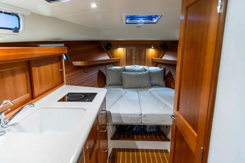 Mare Yacht Photos Pics 2018 MJM 35z yacht interior with cozy bed, wooden cabinetry, and compact kitchen area.