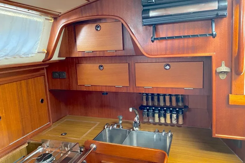 Challanger Yacht Photos Pics Interior of 1992 Hallberg-Rassy 45 yacht kitchen with wooden cabinets and spice rack.