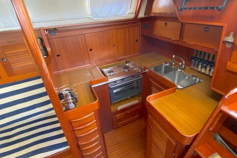 Challanger Yacht Photos Pics Cozy 1992 Hallberg-Rassy 45 yacht kitchen with wood finish, stove, and sink.