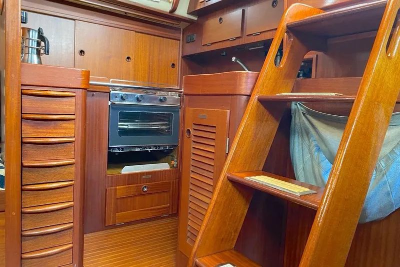 Challanger Yacht Photos Pics Interior of 1992 Hallberg-Rassy 45 yacht with wooden cabinetry and compact kitchen.