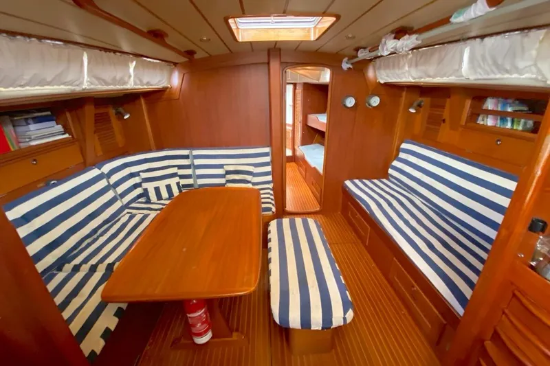 Challanger Yacht Photos Pics Interior of 1992 Hallberg-Rassy 45 yacht with striped seating and wooden finishes.