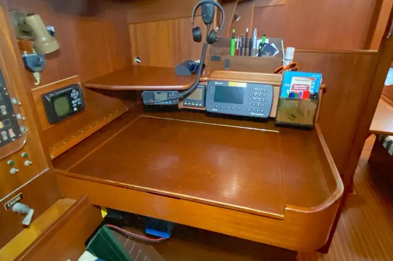 Challanger Yacht Photos Pics Navigation station on 1992 Hallberg-Rassy 45 yacht with communication equipment and wooden finish.