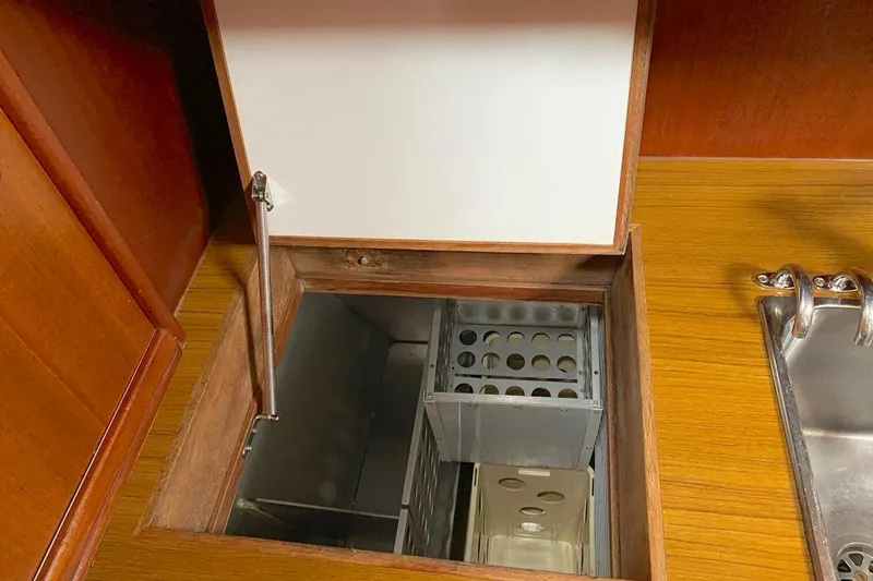 Challanger Yacht Photos Pics Open storage compartment in 1992 Hallberg-Rassy 45 yacht kitchen, featuring wooden and metal elements.